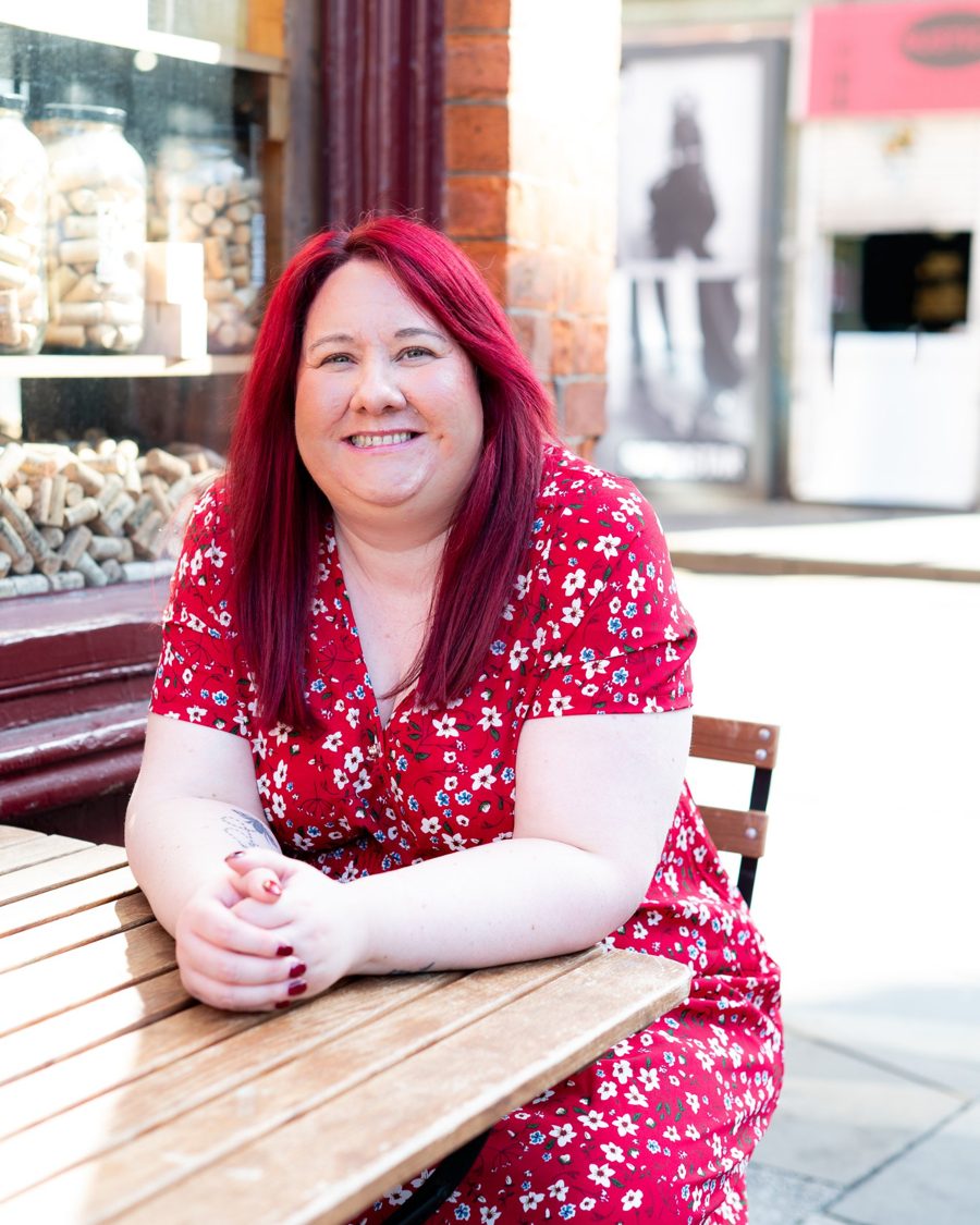 Steph Walch, host of Housing: Off Script, smiling at an outdoor café table